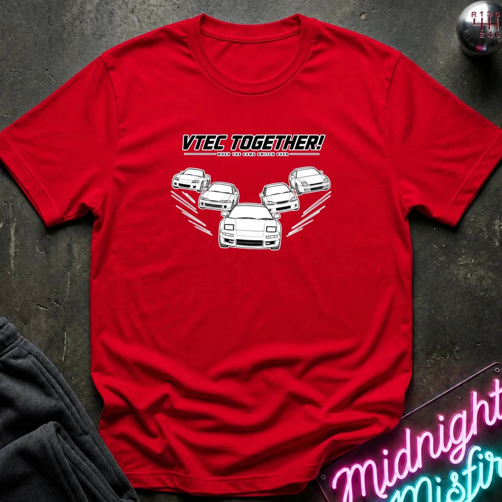 A red short-sleeve graphic T-shirt laid flat on a dark textured surface. The shirt features a white line-art illustration of five cars with the text 'VTEC TOGETHER!' 