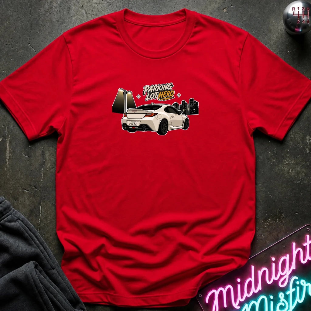 A red  crewneck t-shirt laid flat on a dark textured surface, featuring a graphic of a white sports car with the text 'PARKING LOT HERO'