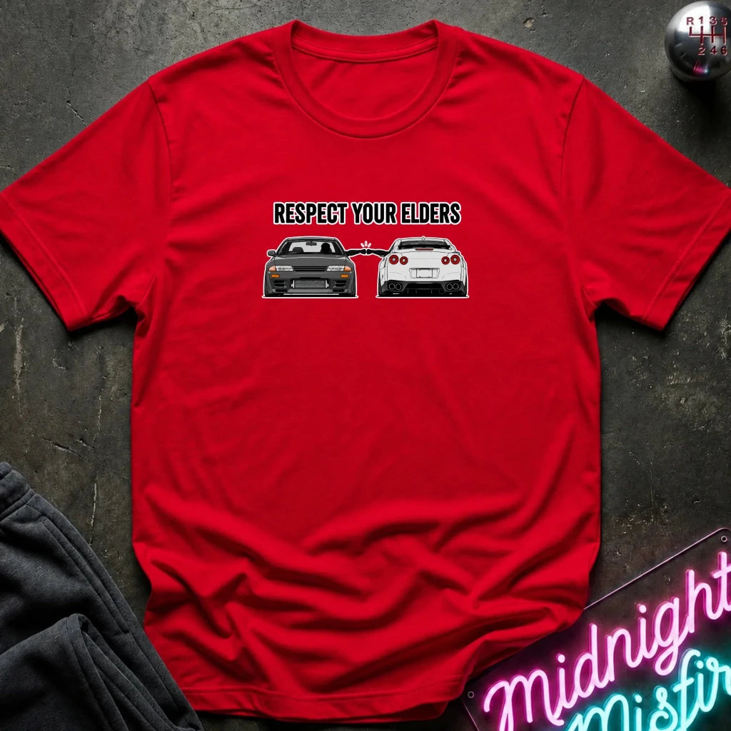 red graphic t-shirt laid flat on a dark textured surface. The graphic features the text and blue car facing a white car.