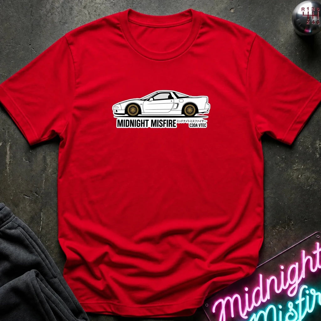 A red short-sleeve t-shirt laid flat on a dark textured surface, featuring a white sports car graphic and the text 'MIDNIGHT MISFIRE '