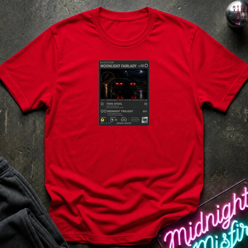 red crewneck t-shirt laid flat on a dark textured surface, featuring a graphic print of vintage card and a car.