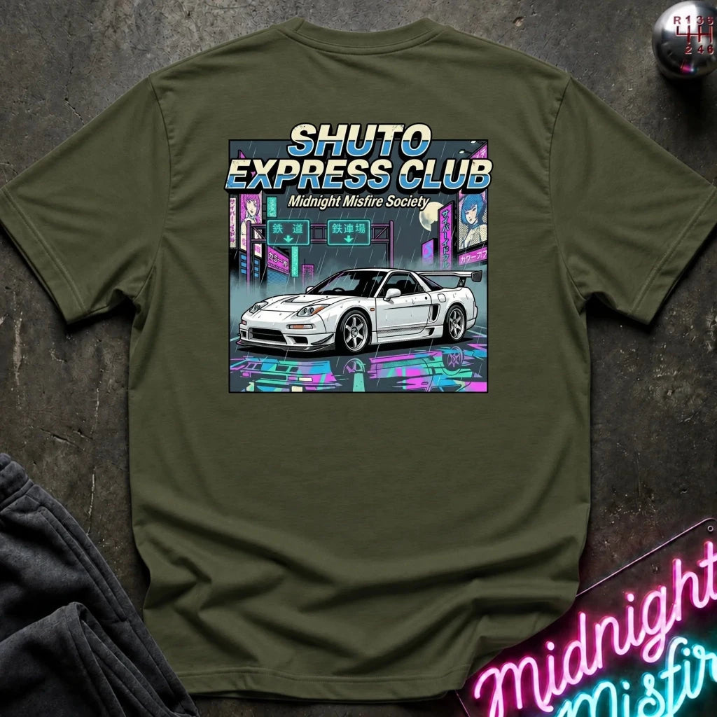 An olive green short-sleeve t-shirt laid flat on a dark textured surface, featuring a large graphic print of a white sports car in a neon cyberpunk city scene with the text 'SHUTO EXPRESS CLUB' and 'Midnight Misfire Society'.