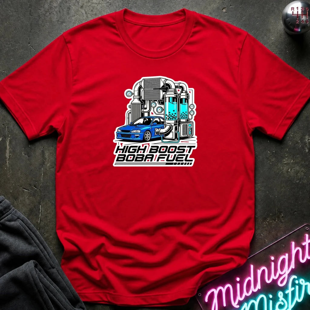 A red short-sleeve crewneck t-shirt laid flat on a dark textured surface. The shirt features a graphic print of a blue sports car with a high-boost turbocharger and the text 'HIGH BOOST BOB A FUEL' in white and black.