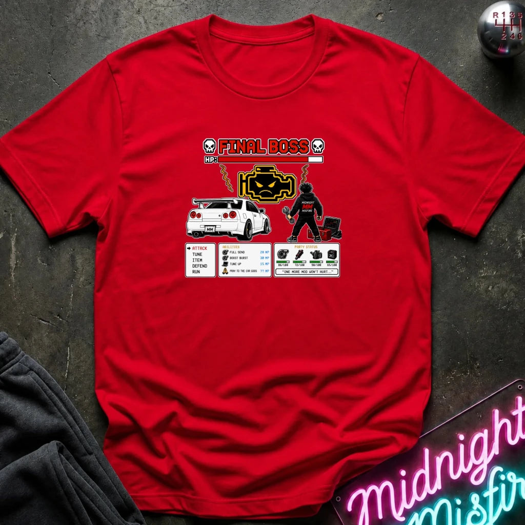 A red short-sleeve graphic t-shirt laid flat on a dark textured surface. The graphic features a white sports car, a pixel-art character, and the text 'FINAL BOSS' with a neon-style design.