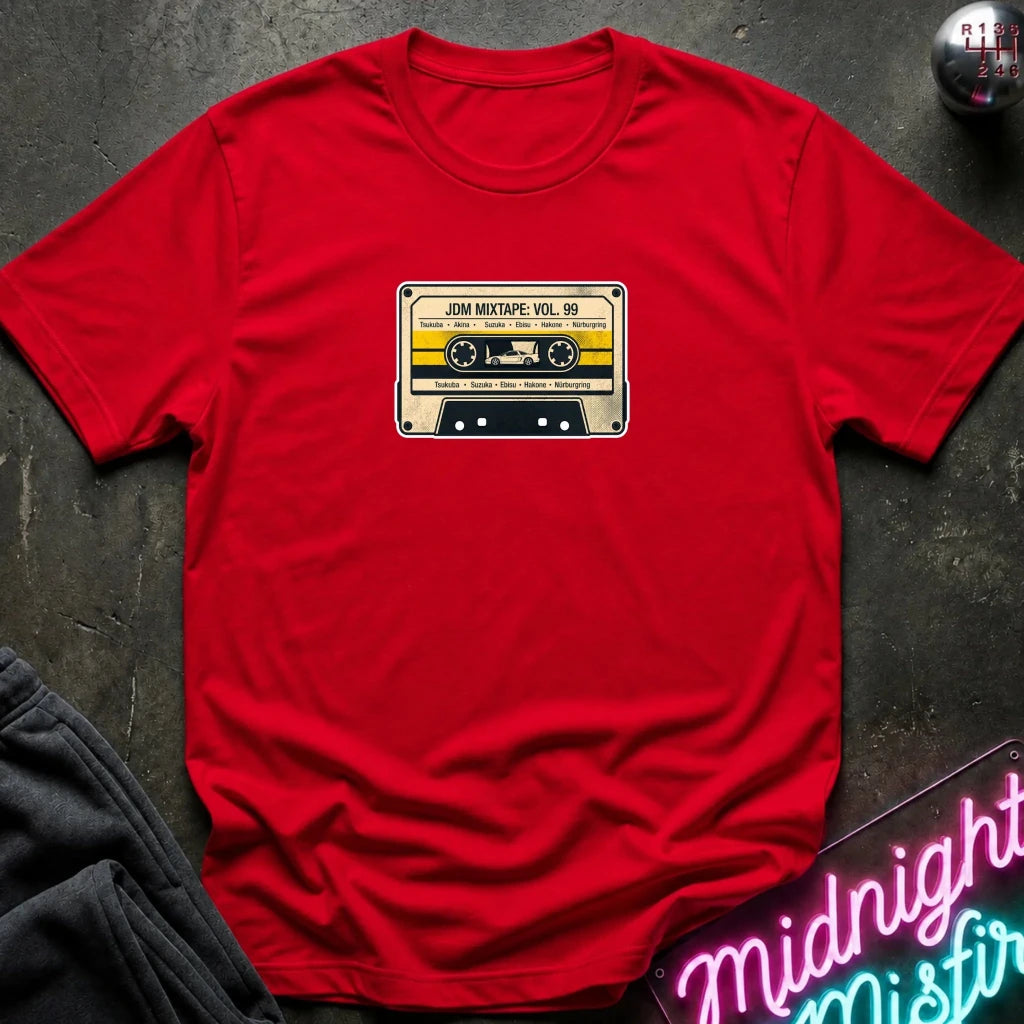 red crewneck t-shirt laid flat on a dark textured surface, featuring a retro cassette tape graphic on the chest with the text 'JDM MIXTAPE VOL.