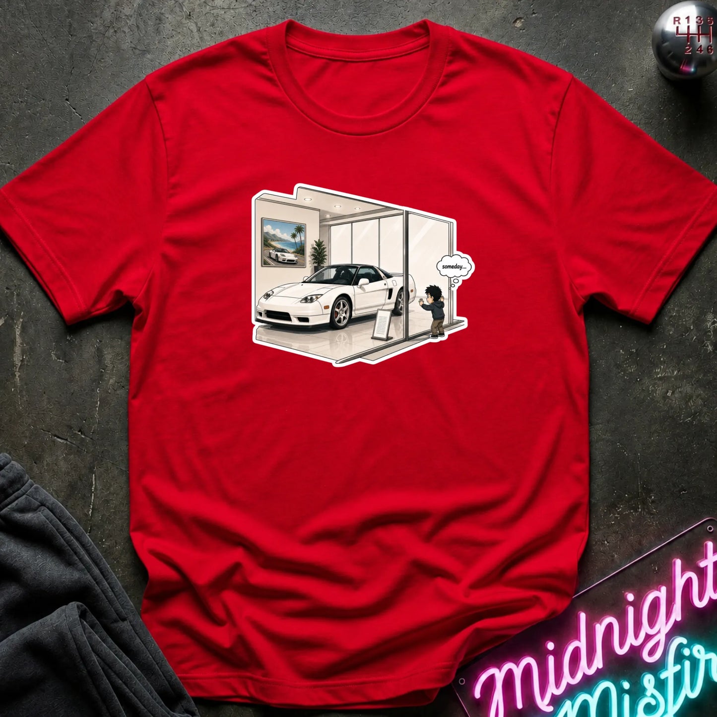 A red short-sleeve crewneck t-shirt featuring a graphic print of a white sports car inside a modern glass showroom with a cartoon character, laid flat on a dark textured surface.