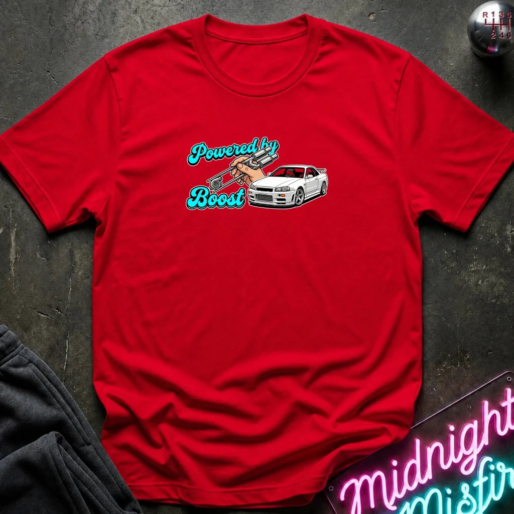 A red short-sleeve crewneck t-shirt laid flat on a dark textured surface. The shirt features a graphic on the chest with the text 'Powered by Boost' in teal and white, alongside an illustration of a white sports car.