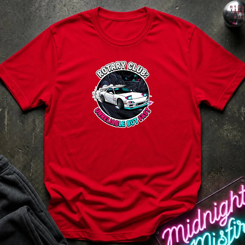 red crewneck t-shirt laid flat on a dark textured surface. The shirt features a circular graphic print in the center showing a white sports car with blue and pink accents, surrounded by the text 'ROTARY CLUB!