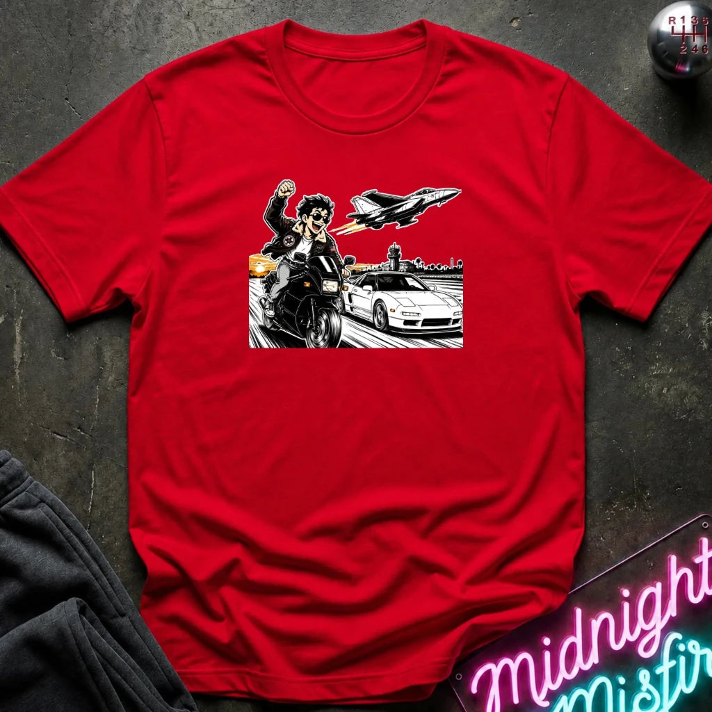 A red short-sleeve crewneck t-shirt featuring a graphic print of a motorcycle racer, a white sports car, and a jet plane, laid flat on a dark textured surface with a neon sign and dark pants partially visible.
