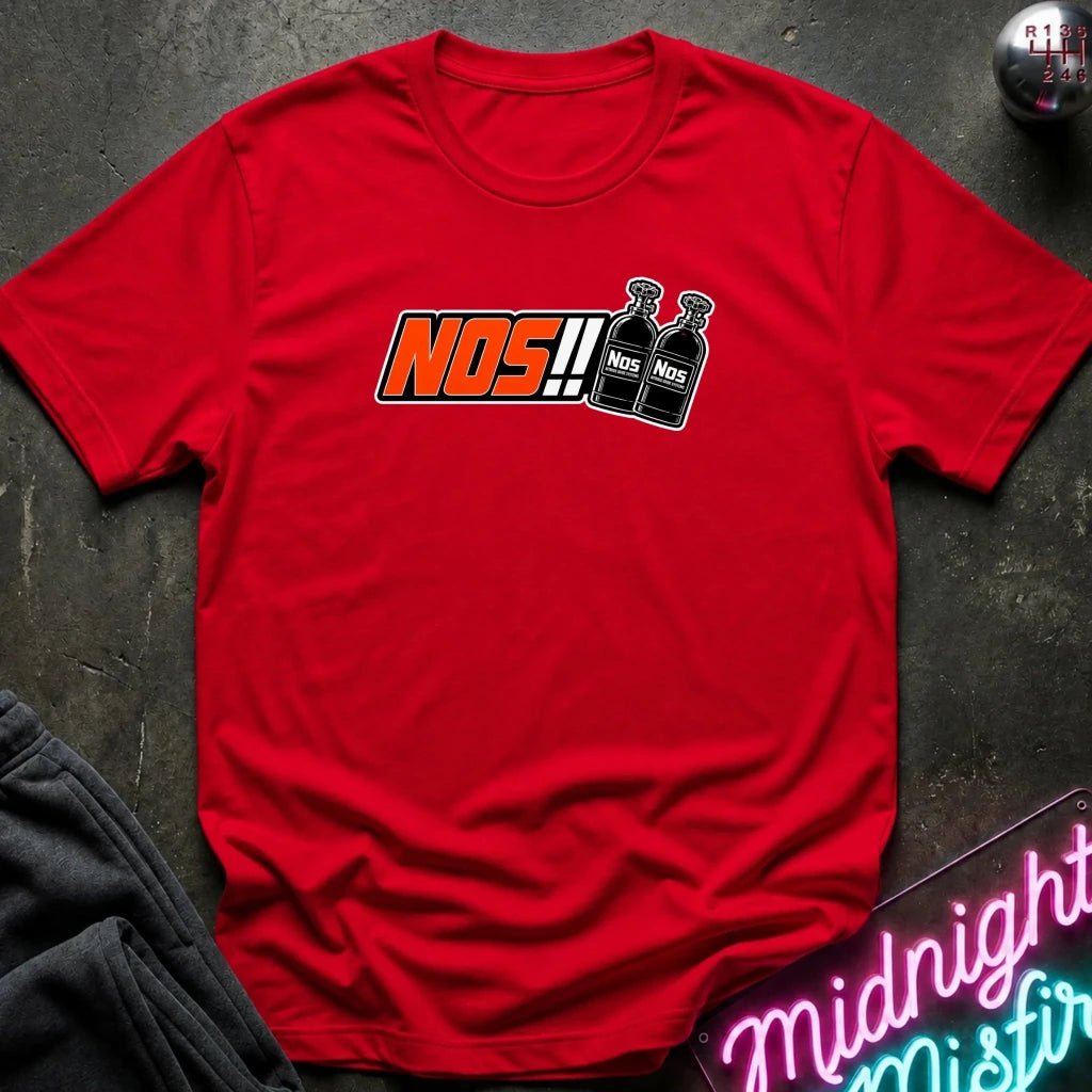 A red short-sleeve t-shirt laid flat on a dark textured surface, featuring a chest graphic that reads 'NOS!!' in orange and black alongside two black spray bottles labeled 'NOS'.