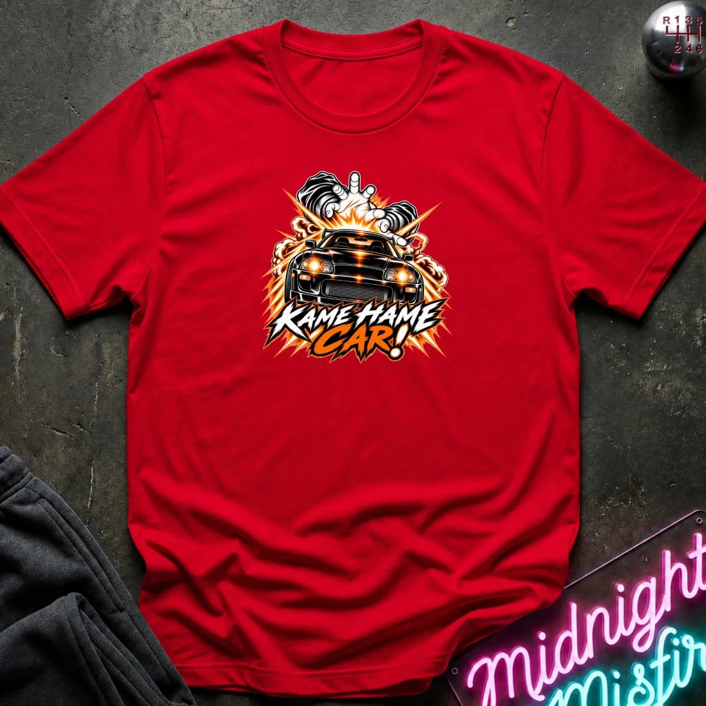 red short-sleeve graphic t-shirt laid flat on a dark textured surface. The shirt features a red, white, and black graphic of a car with the text 'KAME HAME CAR!' in stylized lettering.