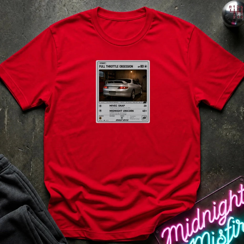 red crewneck t-shirt laid flat on a dark textured surface. The shirt features a graphic print styled like a retro card