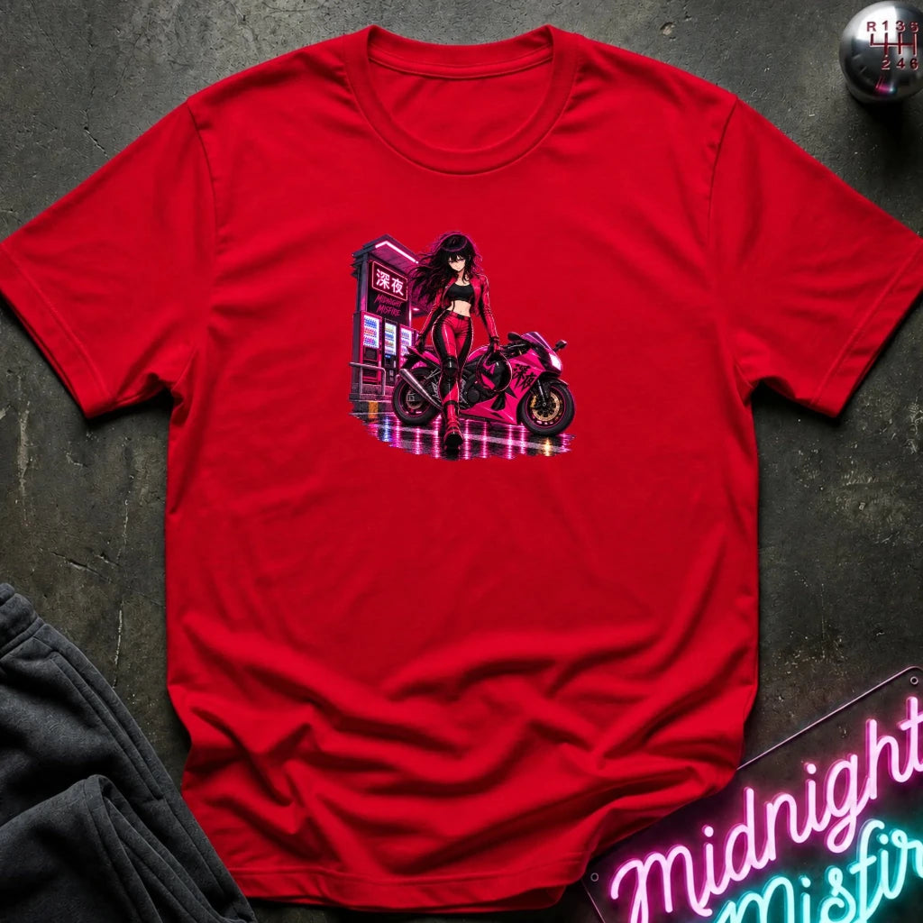 A red short-sleeve crewneck t-shirt laid flat on a dark textured surface, featuring a colorful graphic print of an anime-style woman with a motorcycle. 