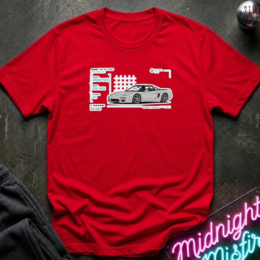 A red short-sleeve crewneck t-shirt featuring a white graphic of a sports car next to stylized text, laid flat on a dark textured surface with a gray sweatshirt and a neon sign partially visible.