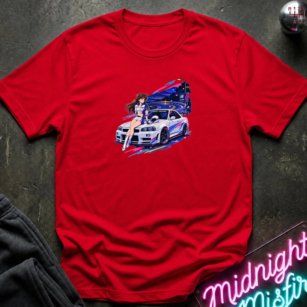 A red s short-sleeve t-shirt laid flat on a dark textured surface, featuring a colorful graphic print of a white sports car and a woman in a neon-lit scene. 