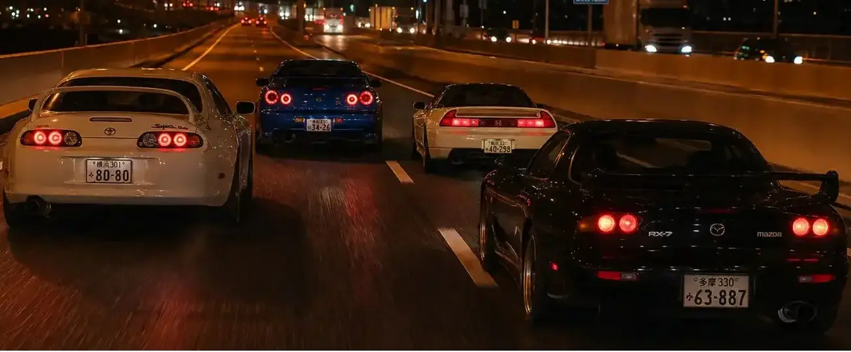 Four sports cars traveling in the same lane on a highway at night, photographed from behind. 