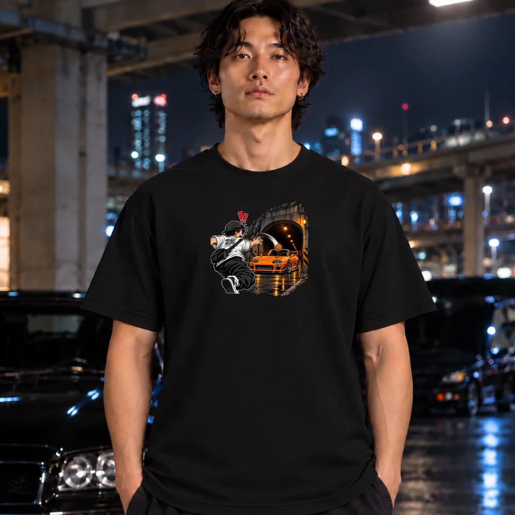 man wearing a black t-shirt and the center of the shirt features a graphic print of an anime character in a black and white outfit with a hat, next to a sports car 