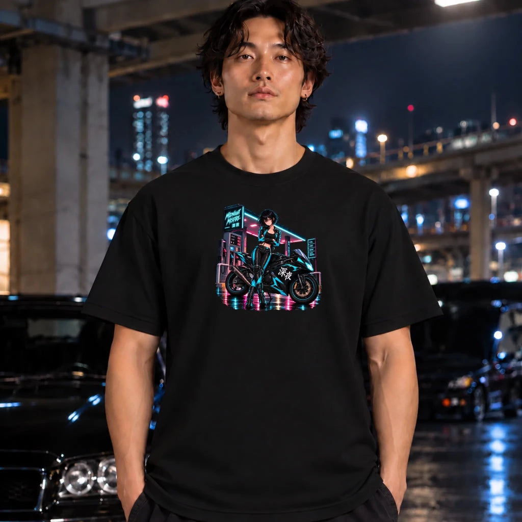 A man wearing a black graphic t-shirt with a colorful neon motorcycle design, standing in a city parking structure at night.