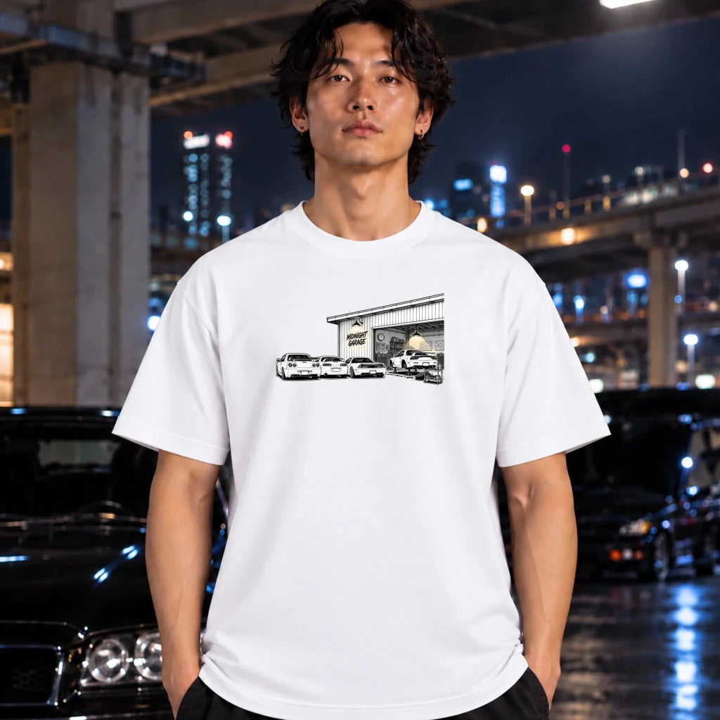 a white short-sleeve t-shirt worn by a man, featuring a black and white graphic print of a garage with several cars in front. 