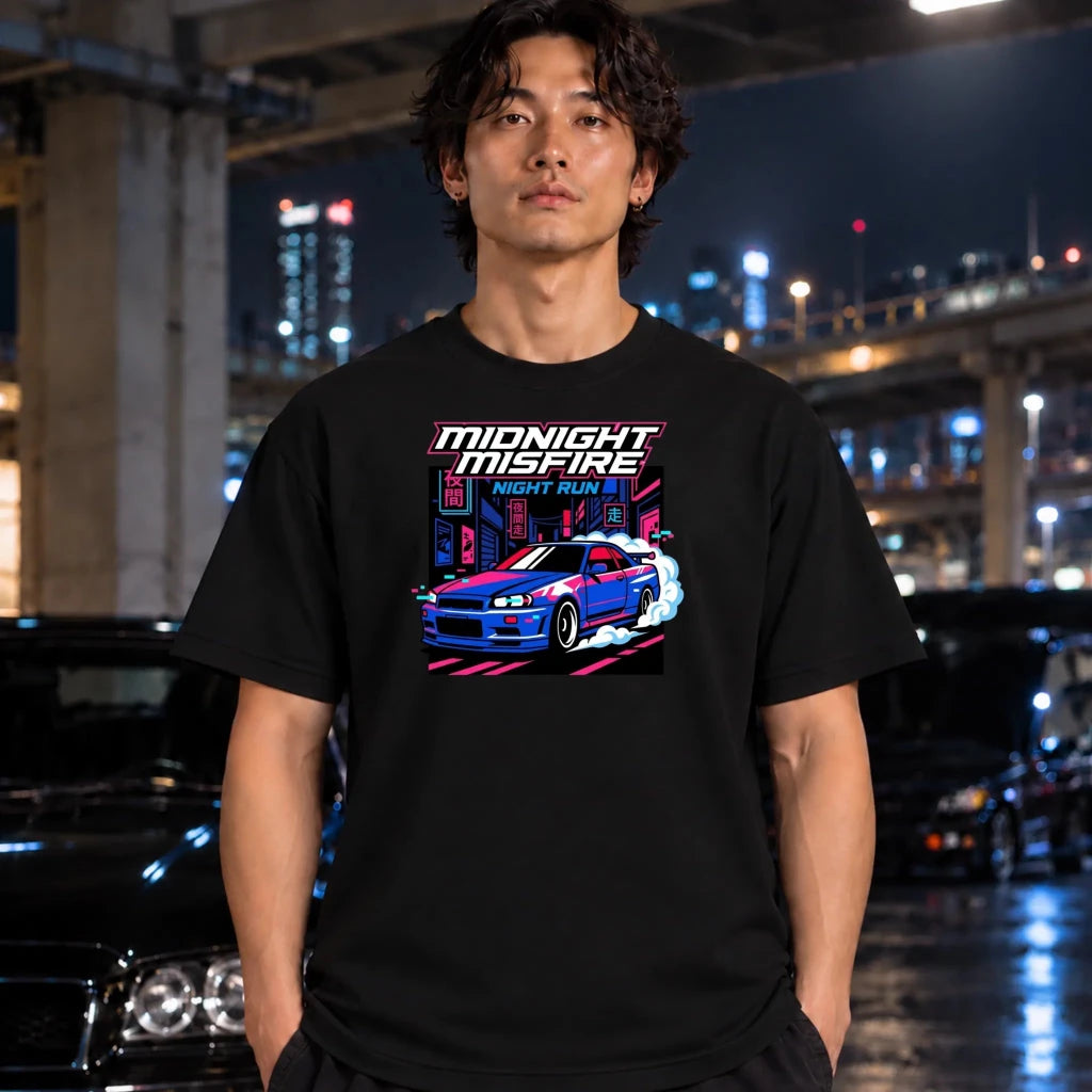 A man wearing a black graphic t-shirt with a blue and pink sports car design and the text 'MIDNIGHT MISFIRE' and 'NIGHT RUN '. The background is a blurred night city scene with cars and lights.