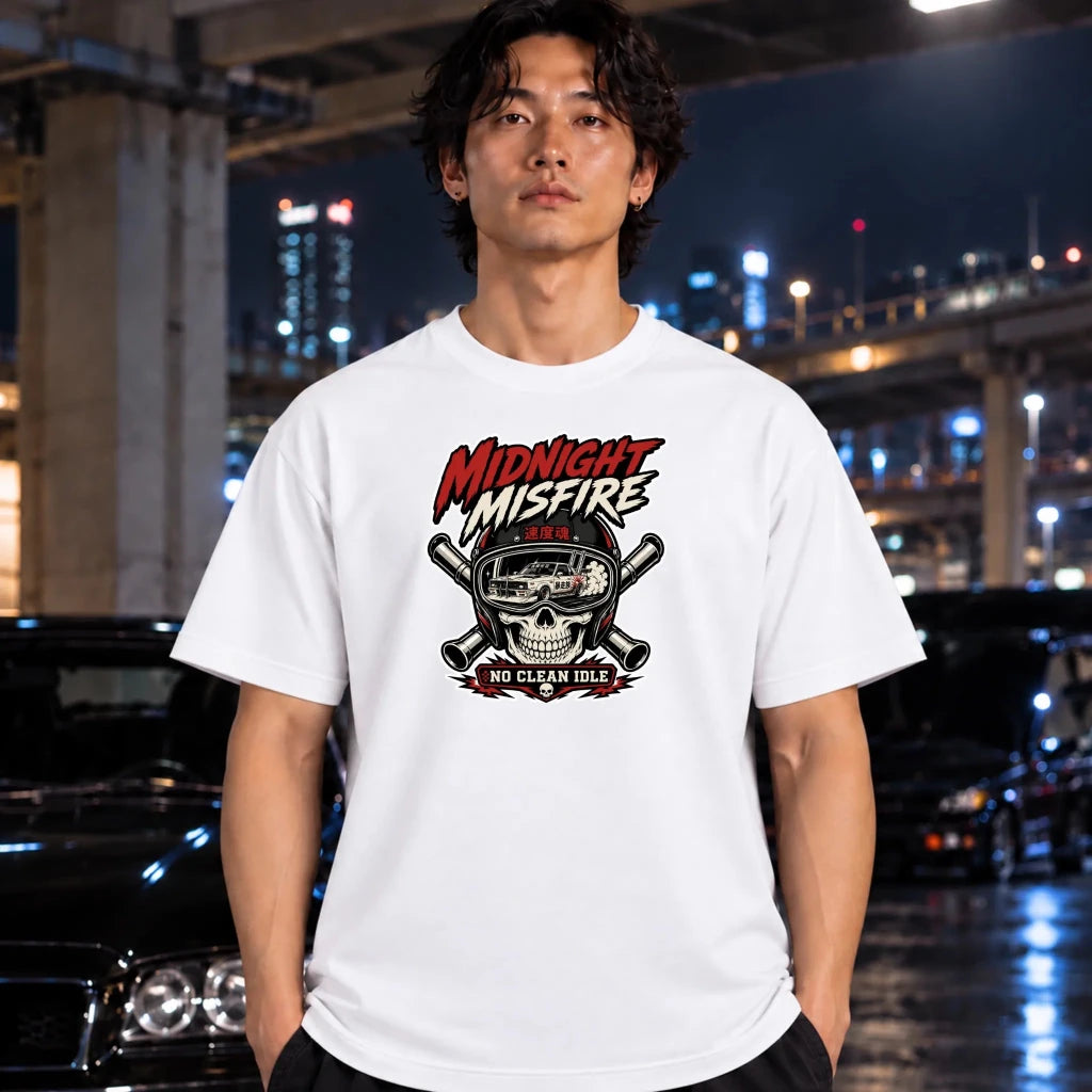 A man wearing a white graphic t-shirt with a 'Midnight Misfire' skull and cross pipes design, standing in a wet urban night environment with blurred cars and lights in the background.