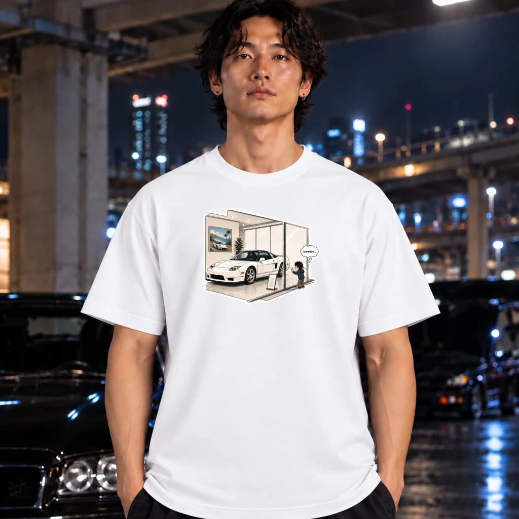A man wearing a white graphic t-shirt with a cartoon illustration of a white sports car in a showrooom standing in front of a blurred night city background with cars.