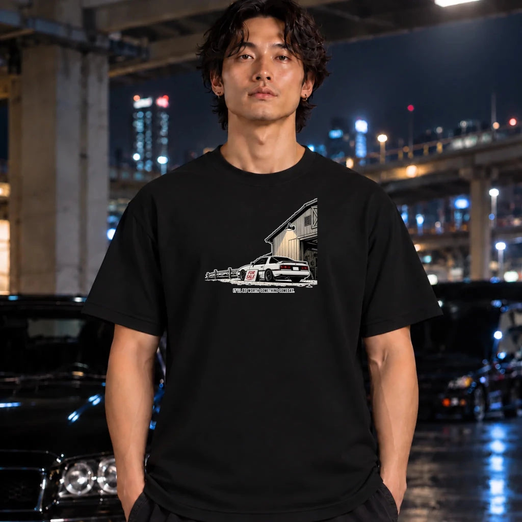 man wearing a black  t-shirt featuring a graphic print of a white muscle car parked in front of a barn