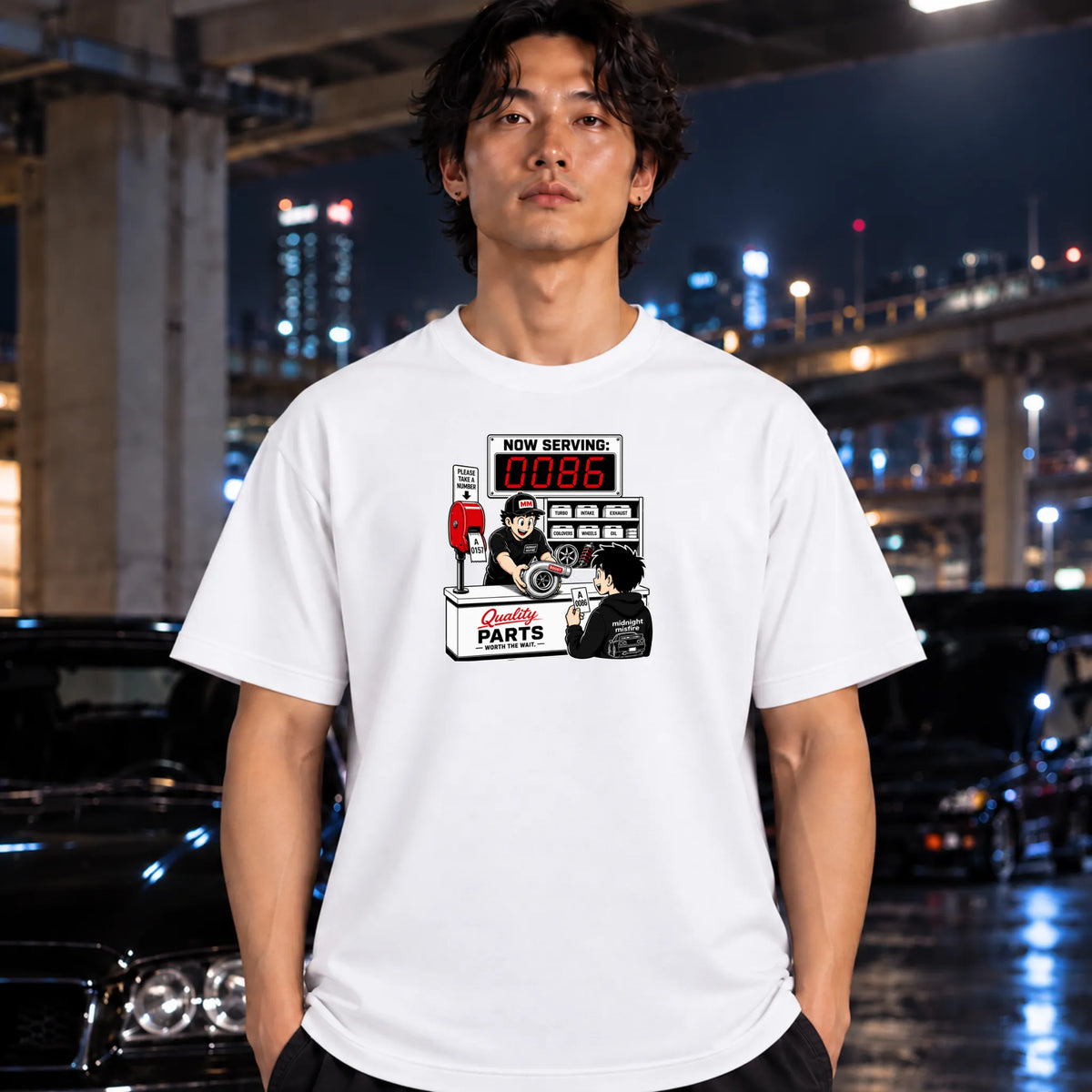 man wearing white crewneck t-shirt with a retro-style graphic of a garage mechanic counter