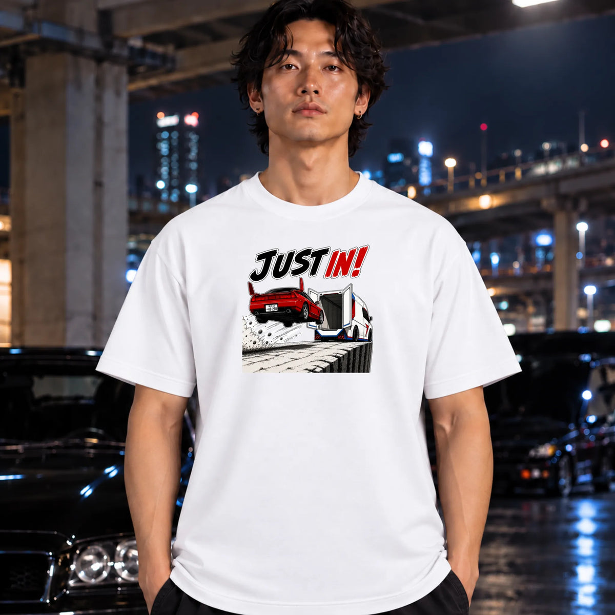 man wearing white short-sleeved t-shirt  that has a red car jumping into back of another machine.