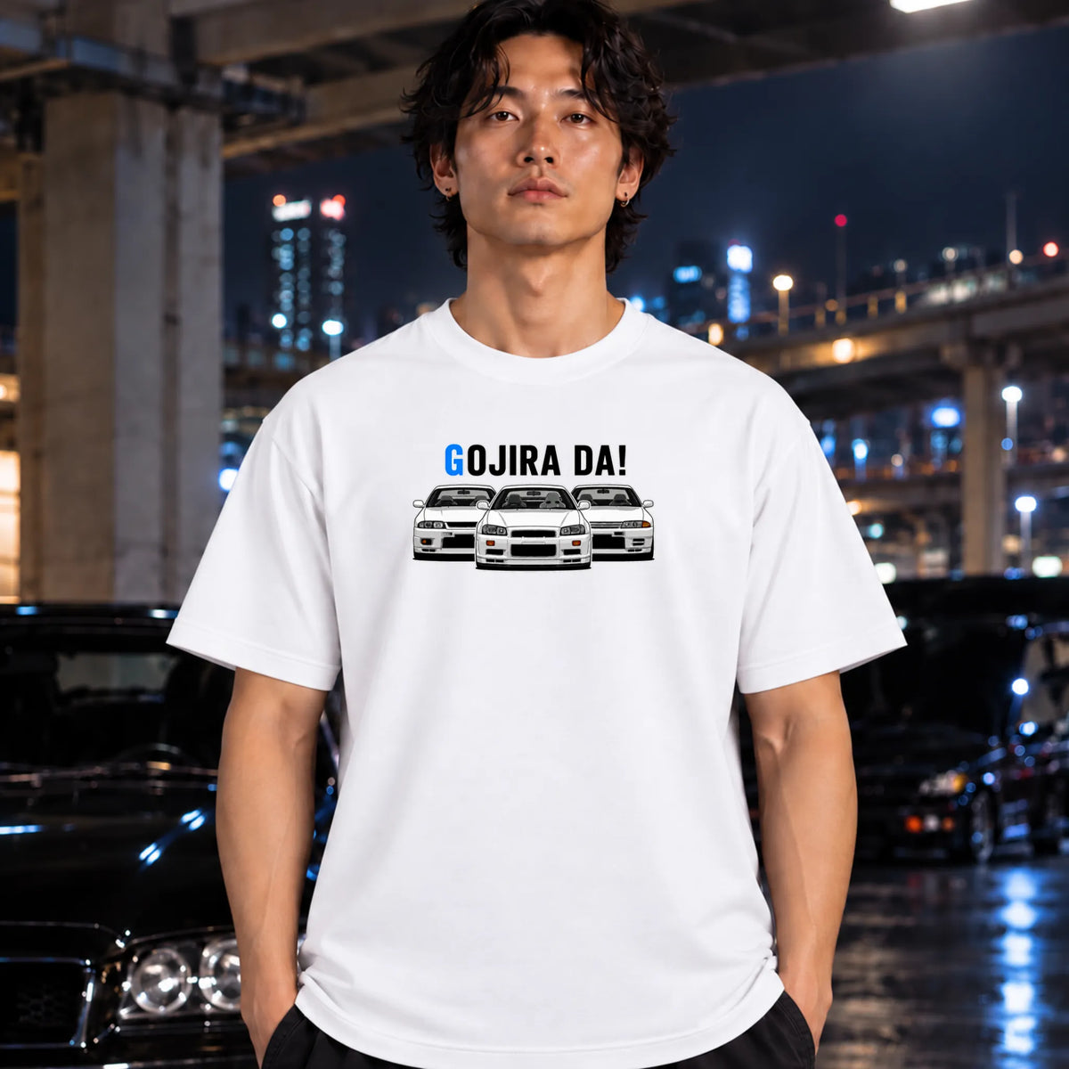 man wearing a white crewneck t-shirt featuring a graphic of three white Nissan Sentra cars with the text 'GOJIRA DA!' printed above them. 