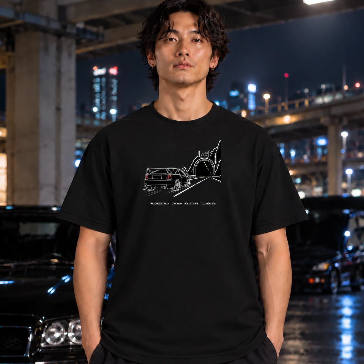man wearing a black t-shirt featuring a black graphic of a classic car in a tunnel with the text.