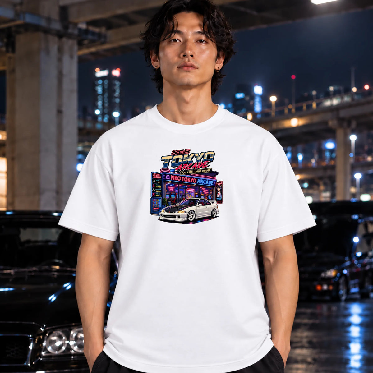 man wearing white short-sleeve t-shirt with a colorful graphic print of a 'Neo Tokyo Arcade" arcade and a black sports car, 