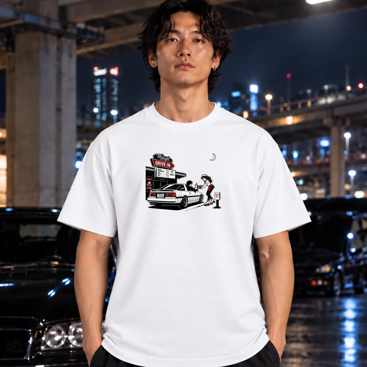A white short-sleeve t-shirt worn by a man, featuring a graphic print of a woman pumping gas at a drive-in station next to a white car. 