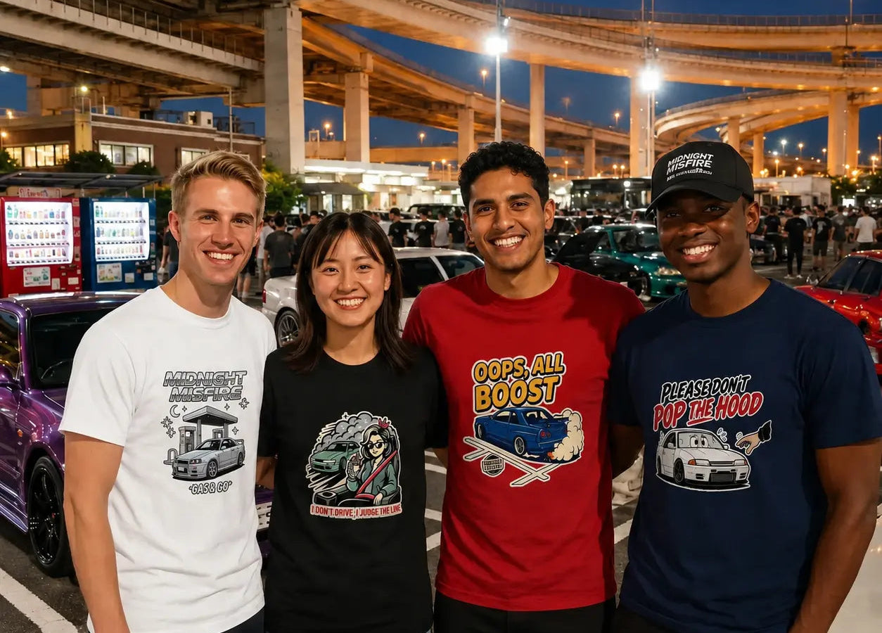 Four peopl standing together outdoors at night in front of highway overpasses and parked cars, each wearing a graphic T-shirt. The shirts feature different designs.