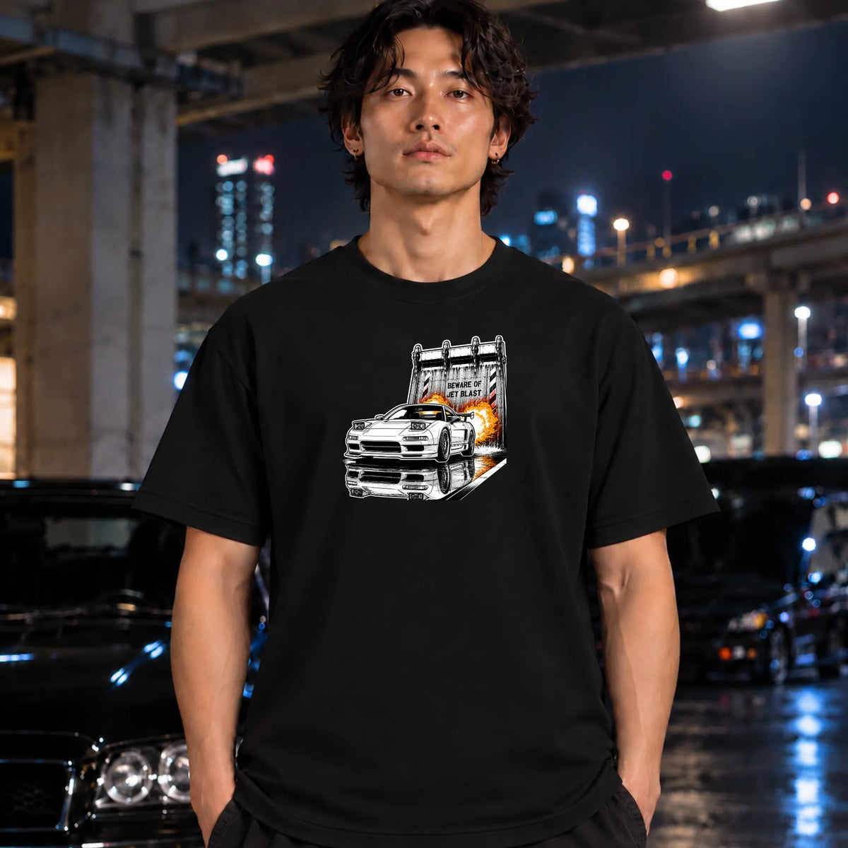 man wearing a black  short-sleeve t-shirt, featuring a graphic print of a white sports car in front of a blast off area.